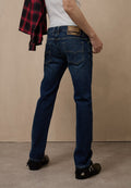 Dunkelblaue Jeans aus Denim mit geradem Schnitt, ausgestattet mit einem Leder-Label auf der Rückseite, zwei Gesäßtaschen und einer leichten Verwaschung. Kombiniert mit einem rot karierten Hemd.