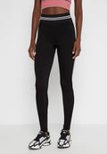 Schwarze Leggings mit figurbetontem Schnitt, ausgestattet mit einem hohen Bund und dünnen weißen seitlichen Streifen, hergestellt aus einem glatten, dehnbaren Stoff.