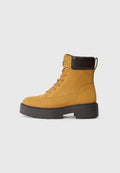 Gelbe Wildleder-Stiefelette mit braunen Akzenten, Schnürdesign, runder Zehenpartie, kräftiger schwarzer Sohle und einem Zugtab am Rücken für einfaches An- und Ausziehen.