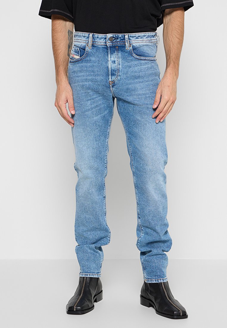 Helleblaue Denim-Jeans im Slim Fit mit einem Fünf-Taschen-Design und einer abgewetzten Waschung, ergänzt durch einen Reißverschluss und einen Metallknopfverschluss.