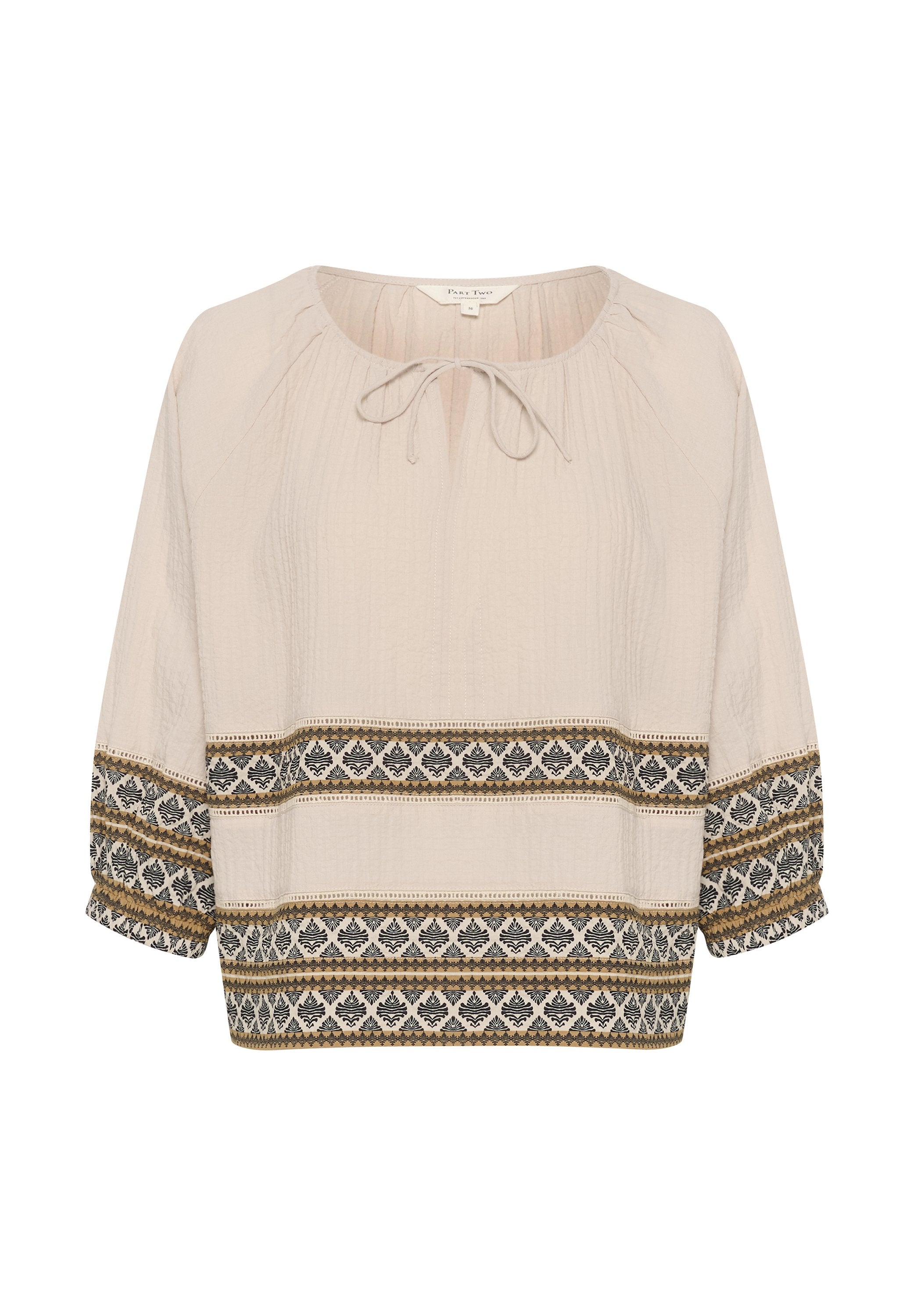 Helle beige Bluse mit rundem Ausschnitt und Bindendetail. Verfügt über kunstvolle schwarze und goldene Stickereien entlang des Saums und der Ärmel.