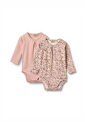 Zwei langärmelige Babybodysuits in sanftem Rosa. Der eine einfarbig mit plisseebesetztem Ausschnitt, der andere mit einem floralen Muster in sanften Farben.