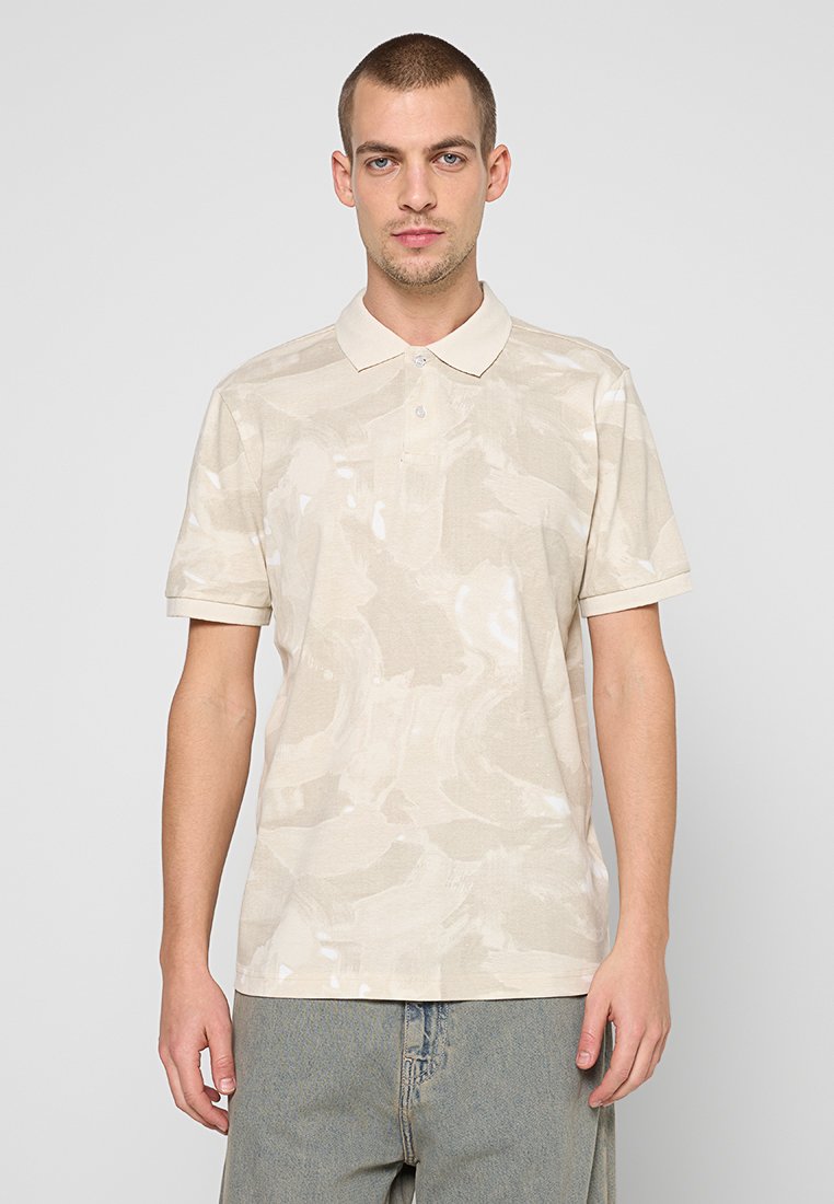 Beiges Poloshirt mit einem dezenten abstrakten Muster, kurzen Ärmeln, einem klassischen Kragen und einer Knopfleiste mit zwei Knöpfen. Leichter Stoff.