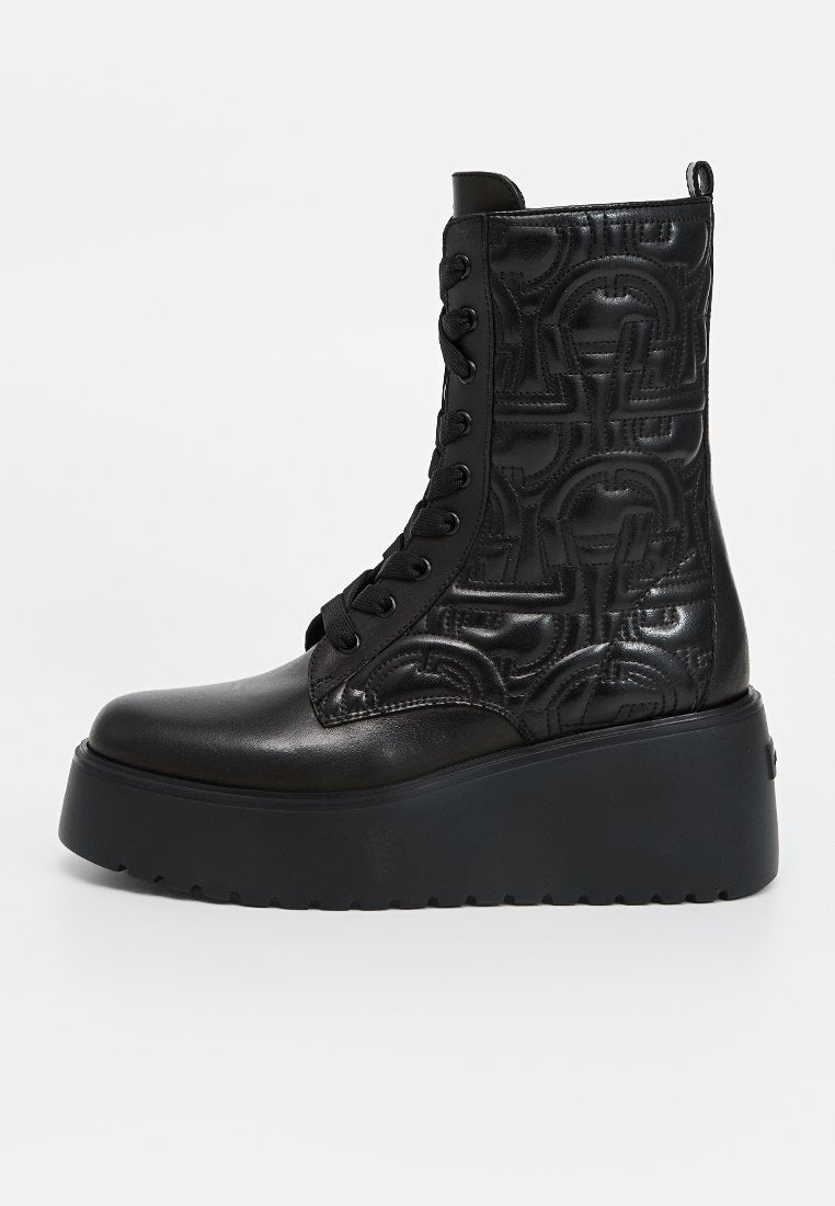 Schwarze, aus Leder gefertigte Schnür-Stiefeletten mit gemusterten Seiten, dicker Plateausohle und betontem Absatz. Verfügen über eine runde Zehenpartie und eine strukturierte Oberfläche.