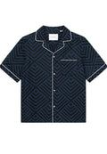 Kurzarmhemd aus navyblauem Stoff mit geometrischem Muster in Blautönen. Auffällige weiße Paspelierung am Kragen und an der Tasche.