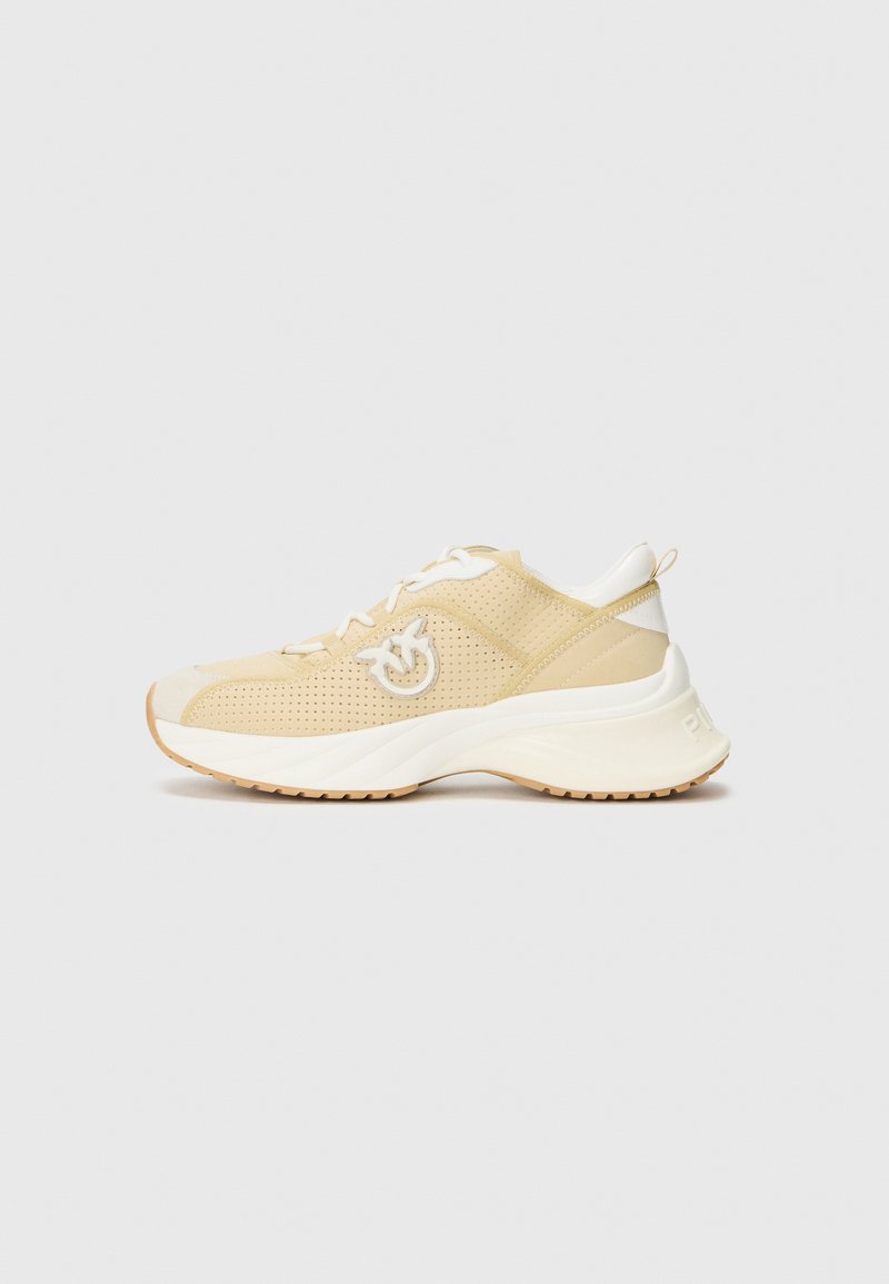 Helle beigefarbene Sportschuhe mit einem perforierten Obermaterial, weißen Akzenten und einer gekrümmten Sohle. Verfügt über ein Logo an der Seite und Schnürsenkel für einen sicheren Sitz.