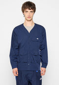 Navyblaue, leichte Jacke mit V-Ausschnitt, langen Ärmeln, zwei Fronttaschen und Logo auf der Brust. Glatte Textur und Druckknopfverschluss.