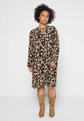 Langärmliges Kleid in Schwarz mit beigem abstraktem Muster, featuring einen Schlüsselloch-Ausschnitt und fließender Silhouette, kombiniert mit tanfarbenen kniehohen Stiefeln.