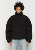 Schwarze Pufferjacke mit hohem Kragen, Frontreißverschluss und zwei seitlichen Taschen. Hat eine gesteppte Textur und eine lockere Passform.