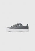 Grauer Sneaker mit einem glatten, synthetischen Obermaterial, runder Spitze, weißer Gummisohle und flachen Schnürsenkeln. Mit dezenten Logodetails an der Seite.