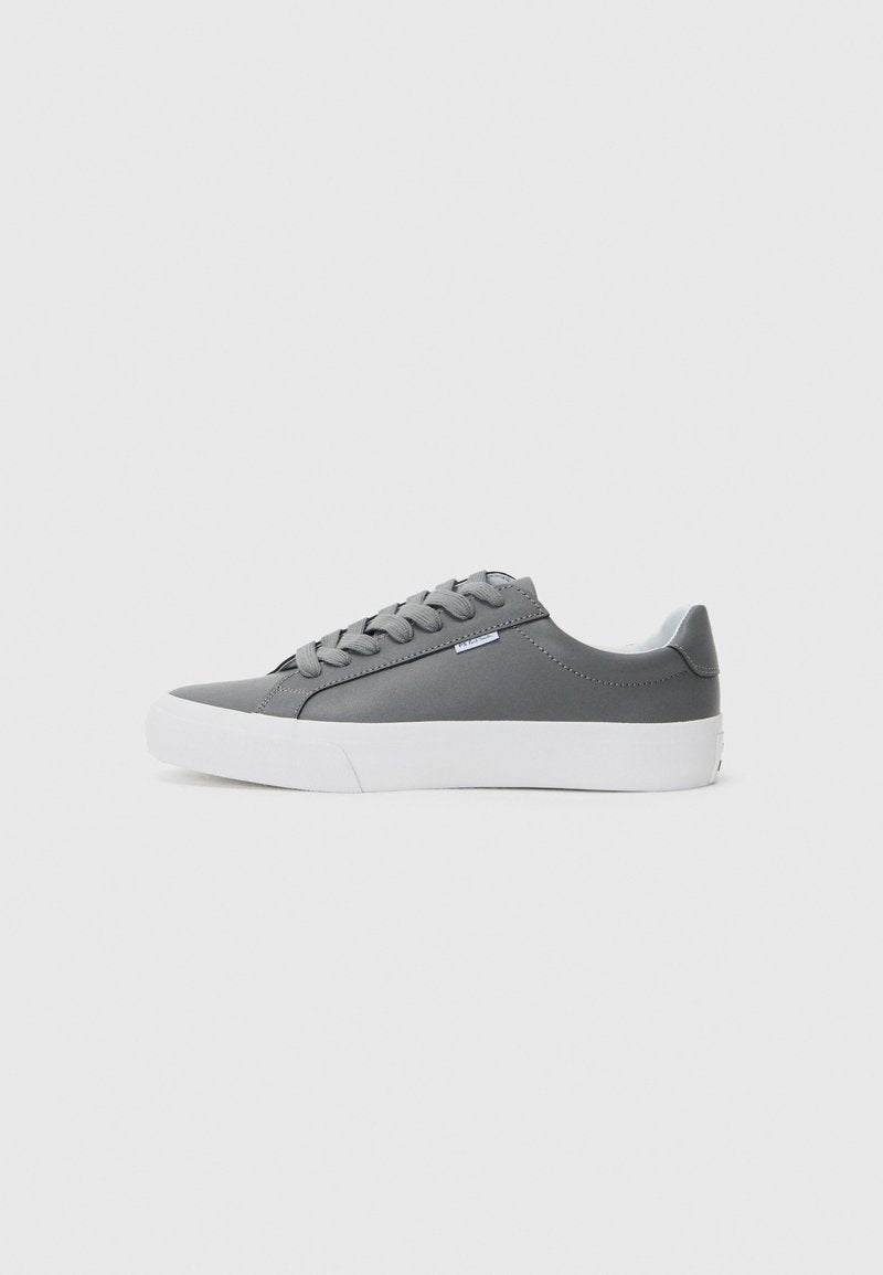 Grauer Sneaker mit einem glatten, synthetischen Obermaterial, runder Spitze, weißer Gummisohle und flachen Schnürsenkeln. Mit dezenten Logodetails an der Seite.