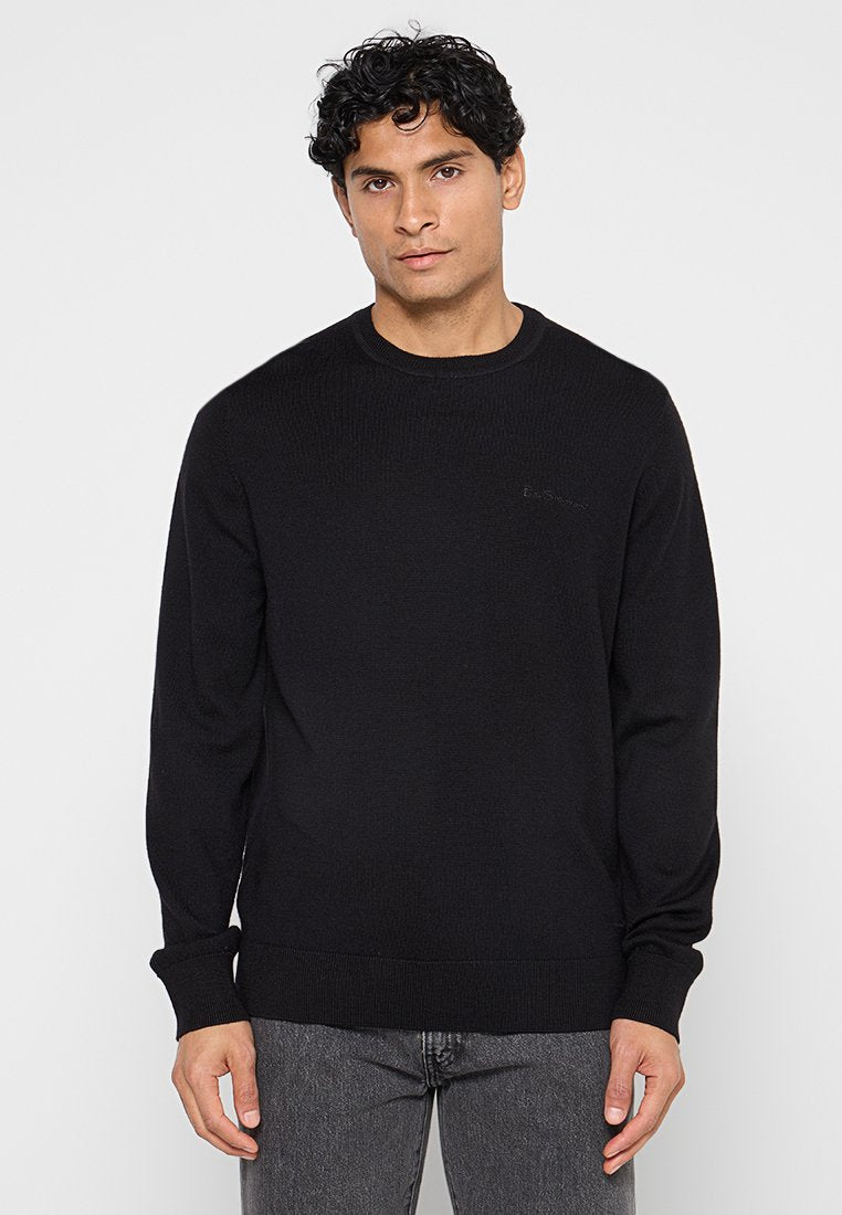 Schwarzer gerippter Pullover mit rundem Ausschnitt und langen Ärmeln; verfügt über dezentes Branding auf der Brust; glatte Textur.