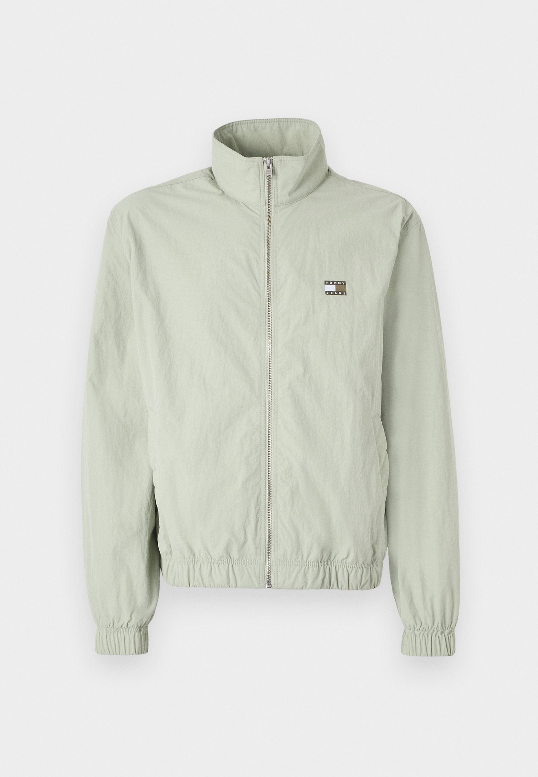 Hellgrüne Zip-Jacke mit hohem Kragen, gerafften Manschetten, elastischem Bund und einem kleinen Logo-Patch auf der linken Brust.