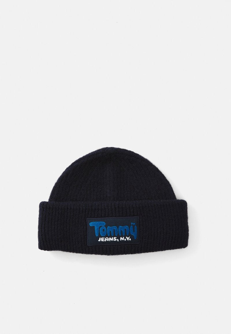 Strickmütze in Dunkelblau mit gerippter Struktur. Mit einem rechteckigen Patch, auf dem "Tommy Jeans, N.Y." in blauer und weißer Schrift zu sehen ist.