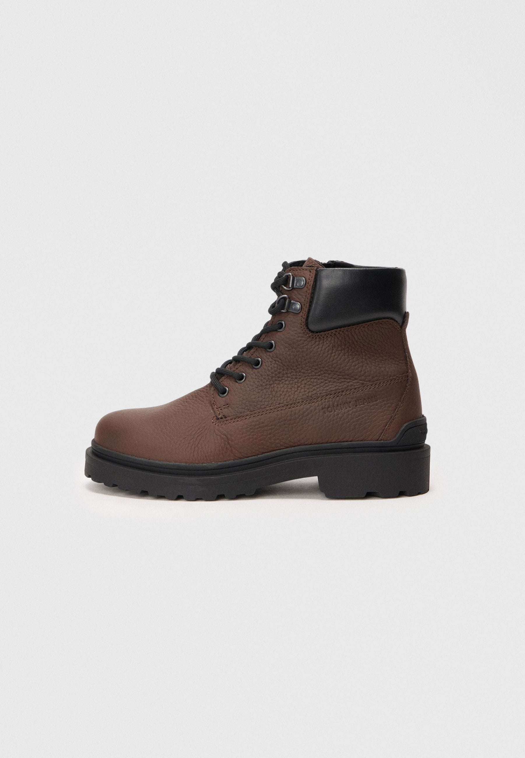 Braune Leder-Stiefelette mit strukturierten Oberflächen, schwarzen Akzenten, runder Zehenform und rutschfester Sohle, ausgestattet mit sechs Ösen für die Schnürsenkel.