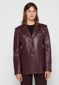 Burgunderfarbener Lederblazer mit zwei Knöpfen, Reverskragen und zwei vorderen Taschen. Glatte Textur und taillierte Passform.