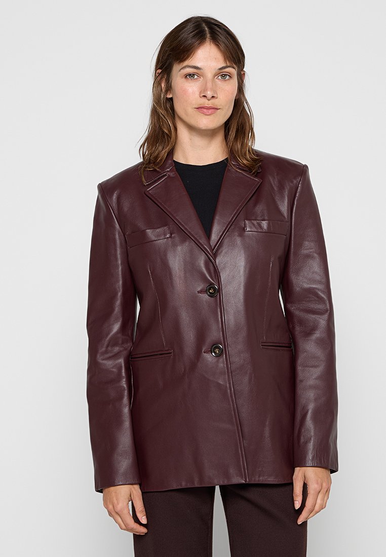 Burgunderfarbener Lederblazer mit zwei Knöpfen, Reverskragen und zwei vorderen Taschen. Glatte Textur und taillierte Passform.