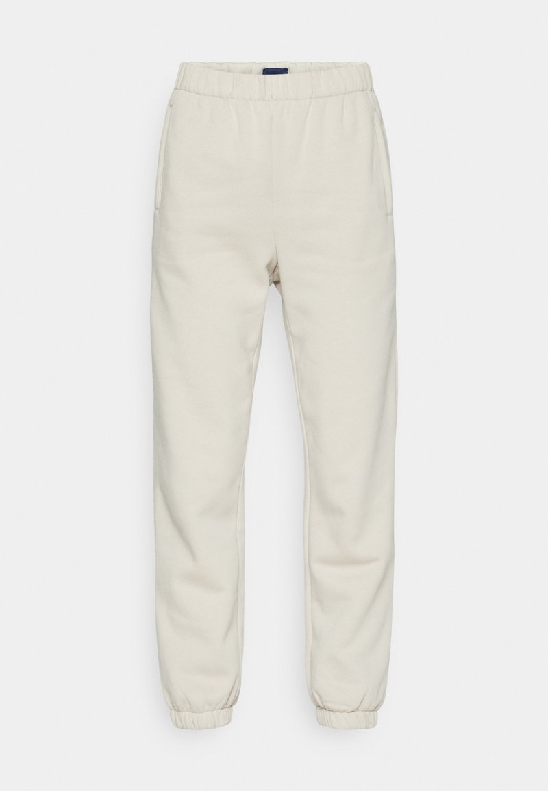 Cremfarbene Sweatpants aus weichem Material, mit einem elastischen Bund, Seitentaschen und Bündchen an den Knöcheln.