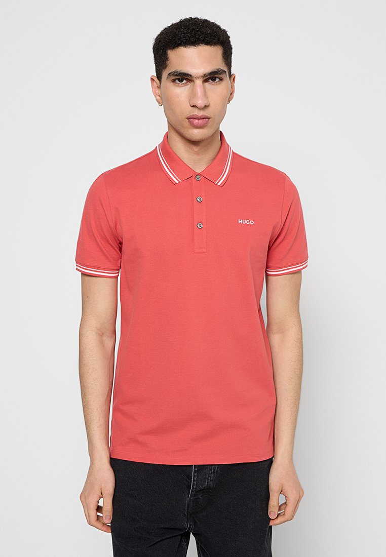 Rotes Poloshirt mit weißgestreiftem Kragen und kurzen Ärmeln, mit drei Knöpfen und einem kleinen Logo auf der Brust. Glatte Baumwolltextur.