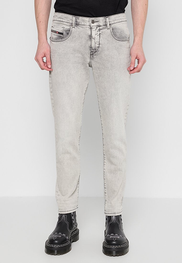 Hellegraue Jeans aus Denim, mit slim fit, Fünf-Taschen-Design und kontrastierenden Nähten, kombiniert mit schwarzen Kampfstiefeln.