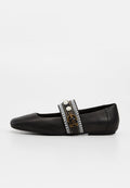 Schwarzer flacher Schuh mit spitzer Zehe, verzierter Riemen mit Perlen, Strasssteinen und einem goldenen Schnallendetail auf weißem Hintergrund.