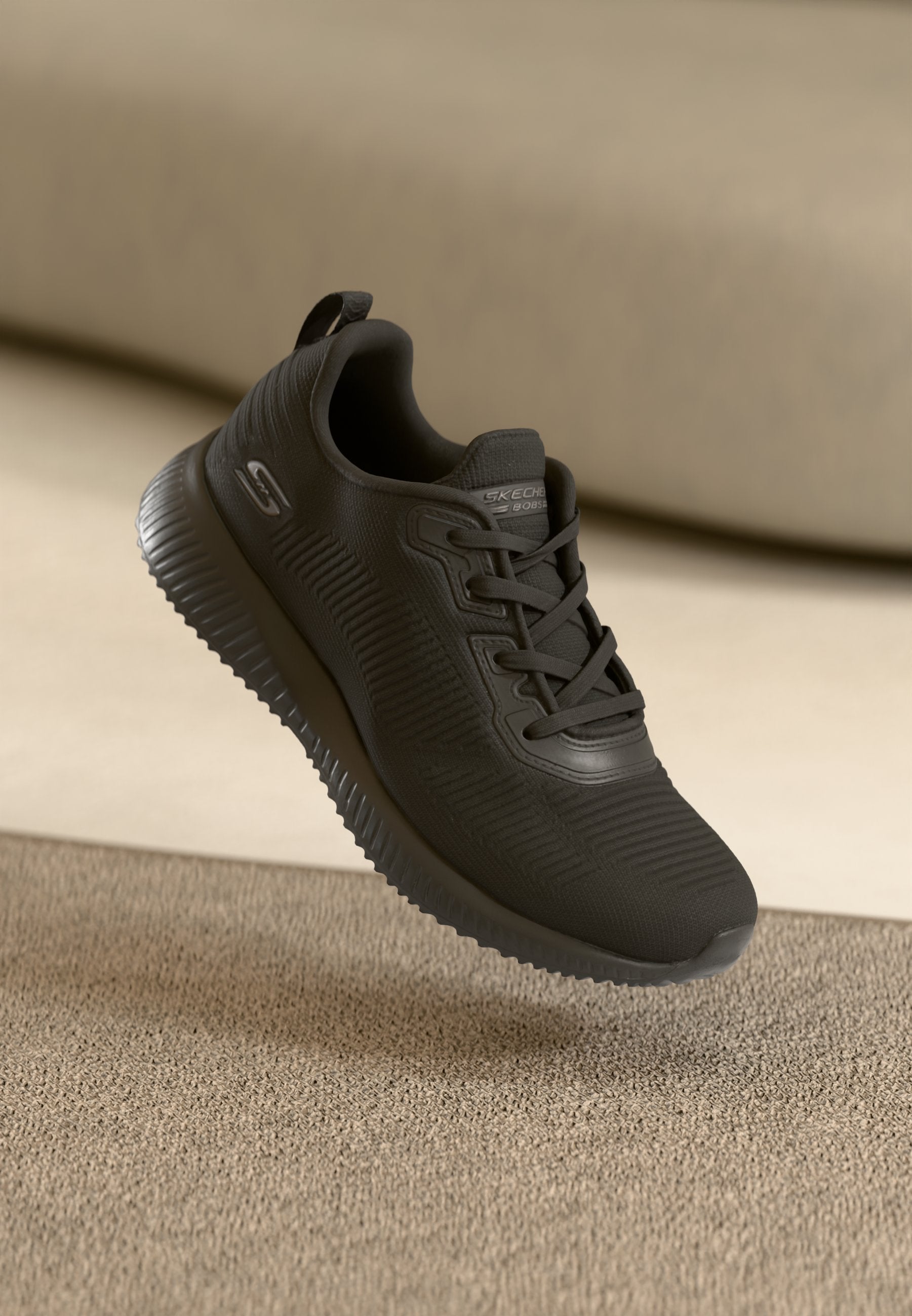 Schwarzer Sportschuh mit strukturiertem Obermaterial und gepolsterter Sohle. Entworfen mit Schnürverschluss und einer Ziehschlaufe für einfaches Anziehen. Glatte Gummisohle.