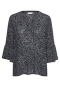 Dunkelblaue Bluse mit V-Ausschnitt, die ein strukturiertes, abstraktes Muster in helleren Farbtönen aufweist. Ausgestellte Ärmel verleihen ein markantes Designelement.