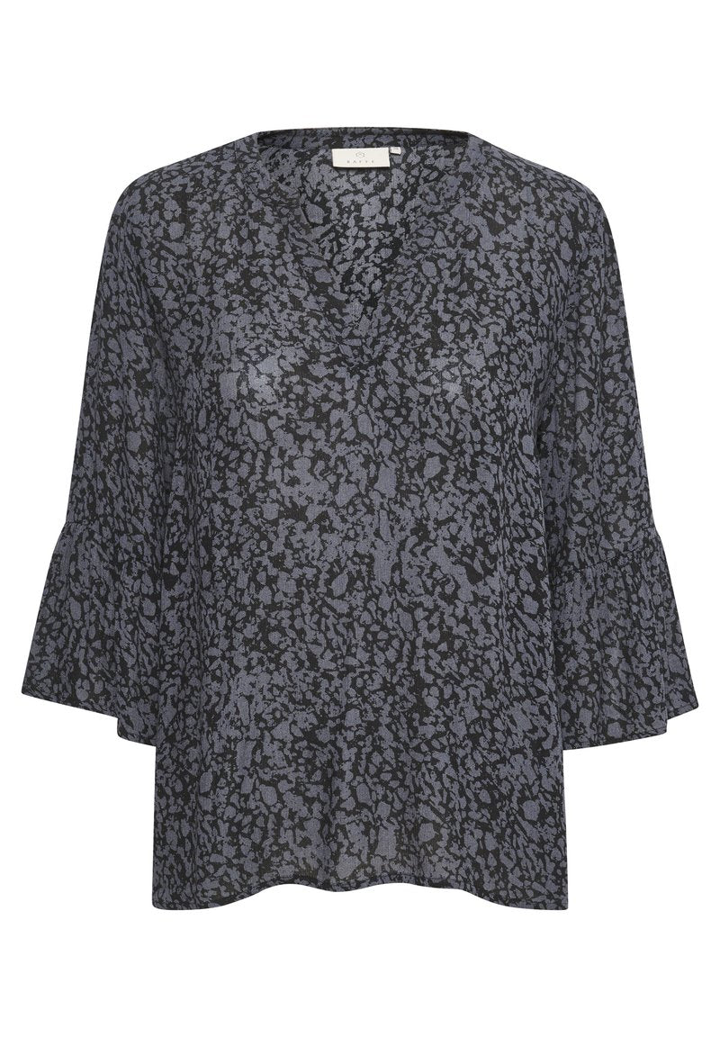 Dunkelblaue Bluse mit V-Ausschnitt, die ein strukturiertes, abstraktes Muster in helleren Farbtönen aufweist. Ausgestellte Ärmel verleihen ein markantes Designelement.