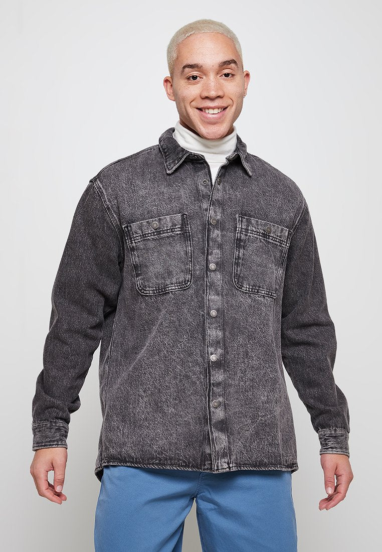 Schwarze Denim-Bluse mit einem verblassten Finish, zwei Vorderaschen, Knopfverschluss und Kragen. Lange Ärmel und lockere Passform.