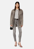 Übergroße graue Denimjacke, graues eng anliegendes T-Shirt, graue Skinny-Jeans, silberne Absatzsandalen, schwarze Handtasche. Merkmale einen lässigen, geschichteten Look.