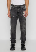 Schwarze, distressed Jeans mit lockerer Passform, versehen mit fransigen Details und einem verblassten Finish. Tragen mit schwarzen Sportschuhen.