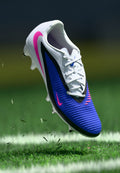 Nike Fußballschuh mit weißem Obermaterial, blauer strukturierter Oberfläche, pinkfarbenen Akzenten und schwarzen Details. Verfügt über eine Schnürung und geformte Stollen.