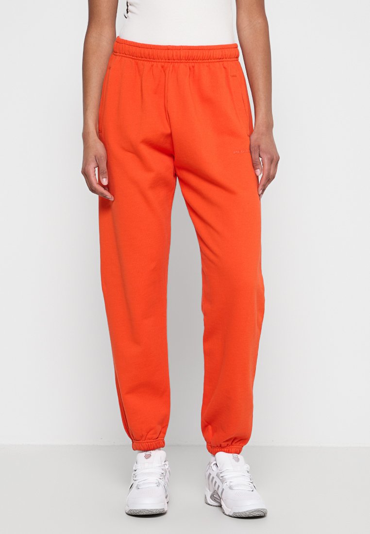 Orange Sweatpants mit lockerer Passform, elastischem Bund, bündchenärmel und dezentem Logodesign. Der Stoff wirkt weich und glatt.
