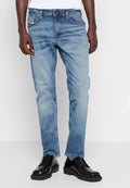 Hellblaue Jeans aus Denim mit leichter Abnutzung, Fünf-Taschen-Design, gerade Passform und kontrastierenden Nähten, kombiniert mit schwarzen Schuhen.