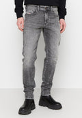 Schmale graue Jeans aus Denim mit einem verblassten Finish, fünf Taschen, Gürtelschlaufen und Kontrastnähten. Kombiniert mit schwarzen Stiefeln.