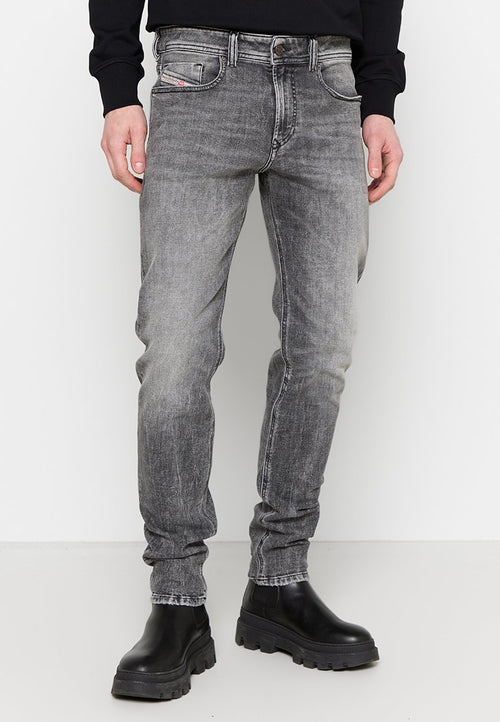 Schmale graue Jeans aus Denim mit einem verblassten Finish, fünf Taschen, Gürtelschlaufen und Kontrastnähten. Kombiniert mit schwarzen Stiefeln.