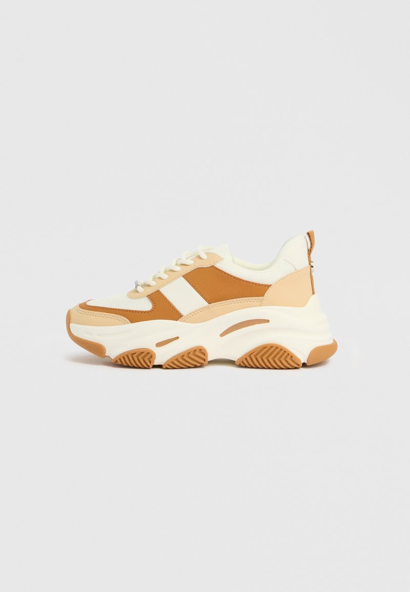 Voluminöse Sneakers in einer Farbpalette aus Creme, Beige und Braun. Sie verfügen über strukturierte Stoffe und glatte Lederflächen, mit einer dicken Sohle und einem gemusterten Profil.
