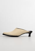 Beige glänzende Mules mit einer spitzen Zehenform, schlankem Design, niedrigem schwarzen Absatz und offener Rückseite. Glatte Textur ohne sichtbare Muster oder Akzente.
