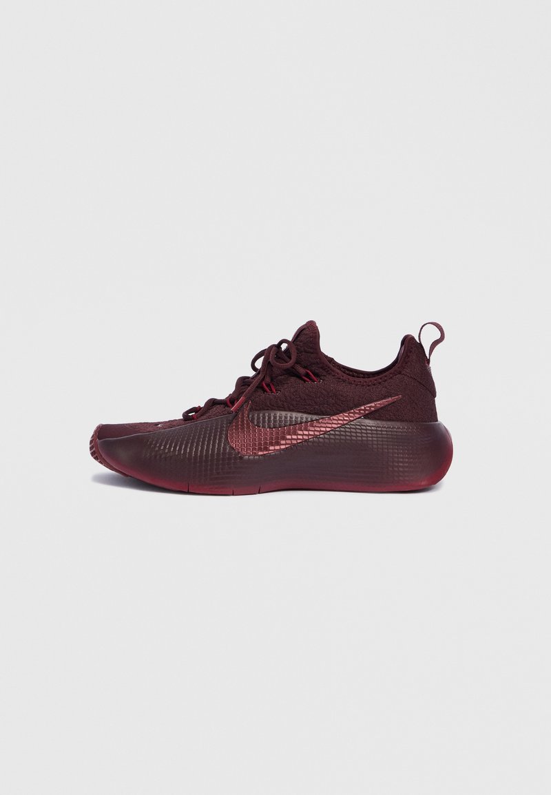 Maroonfarbener Sportschuh mit einer strukturierten Oberseite, einer abgerundeten Zehenpartie, dünnen Schnürsenkeln und einem auffälligen Nike Swoosh-Logo in metallischem Maroon.