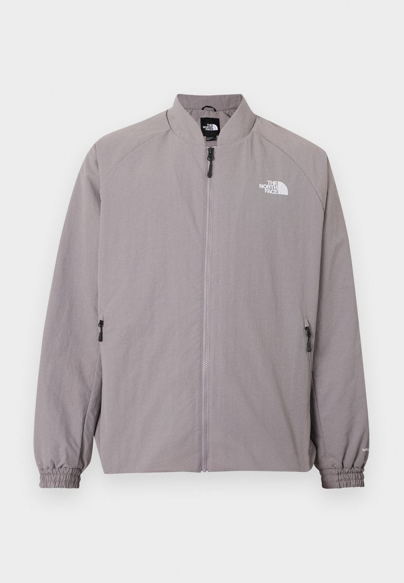 Hellgraue Windjacke mit Stehkragen, durchgehendem Reißverschluss vorne, elastischen Bündchen und seitlichen Reißverschlusstaschen. Mit Logo auf der Brust.