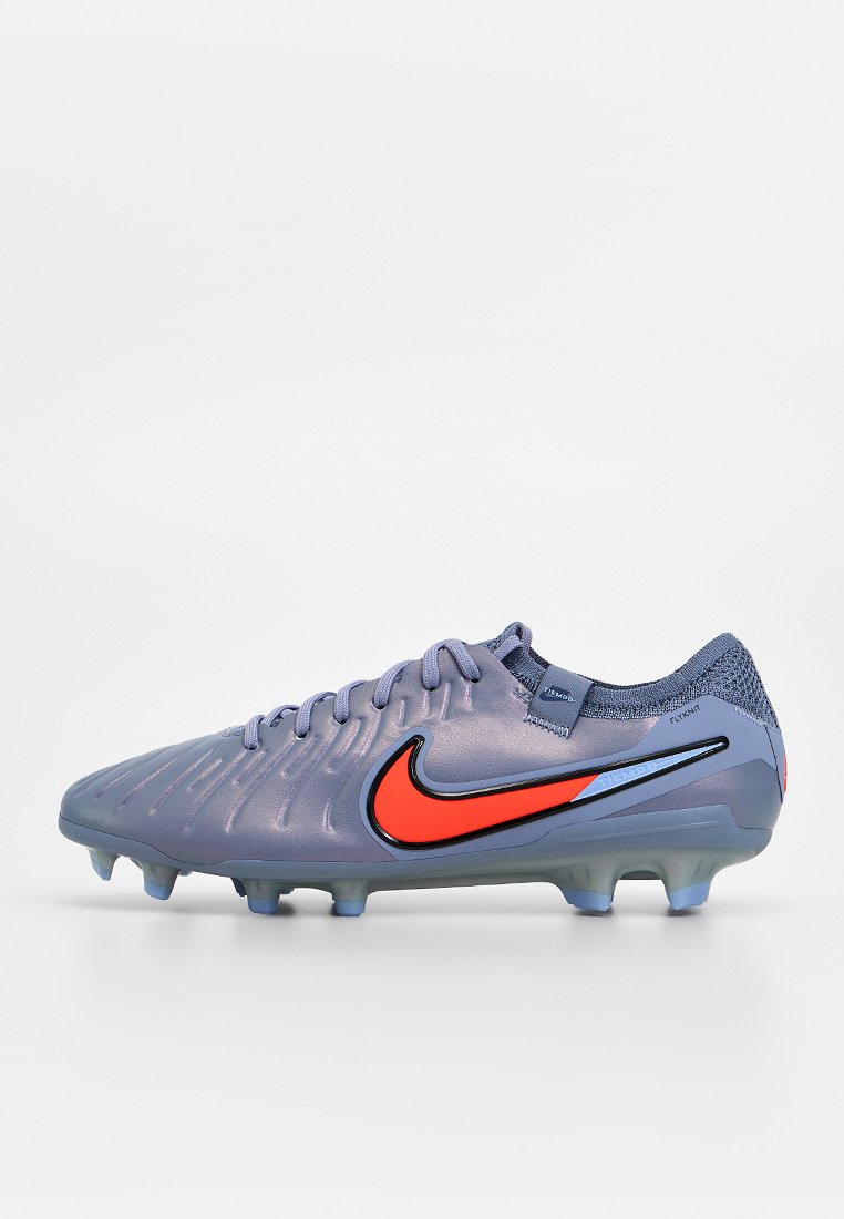 Nike Fußballschuh in Helllila mit strukturiertem Obermaterial, schwarzen und roten Akzenten sowie einem blauen Markenlogo, ausgestattet mit einer geformten Außensohle.