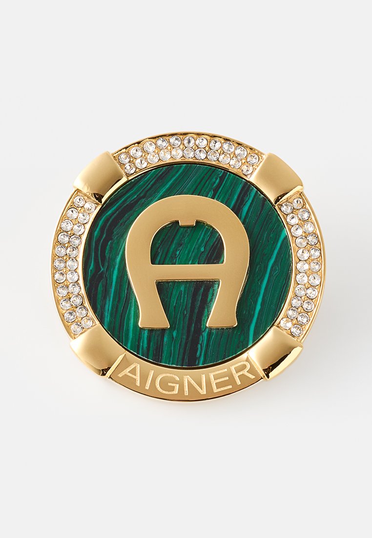 Grüne Malachit-Brosche in kreisförmigem Design mit goldenen Akzenten, die ein zentrales "A"-Logo und einen Rand aus klaren Strasssteinen aufweist.