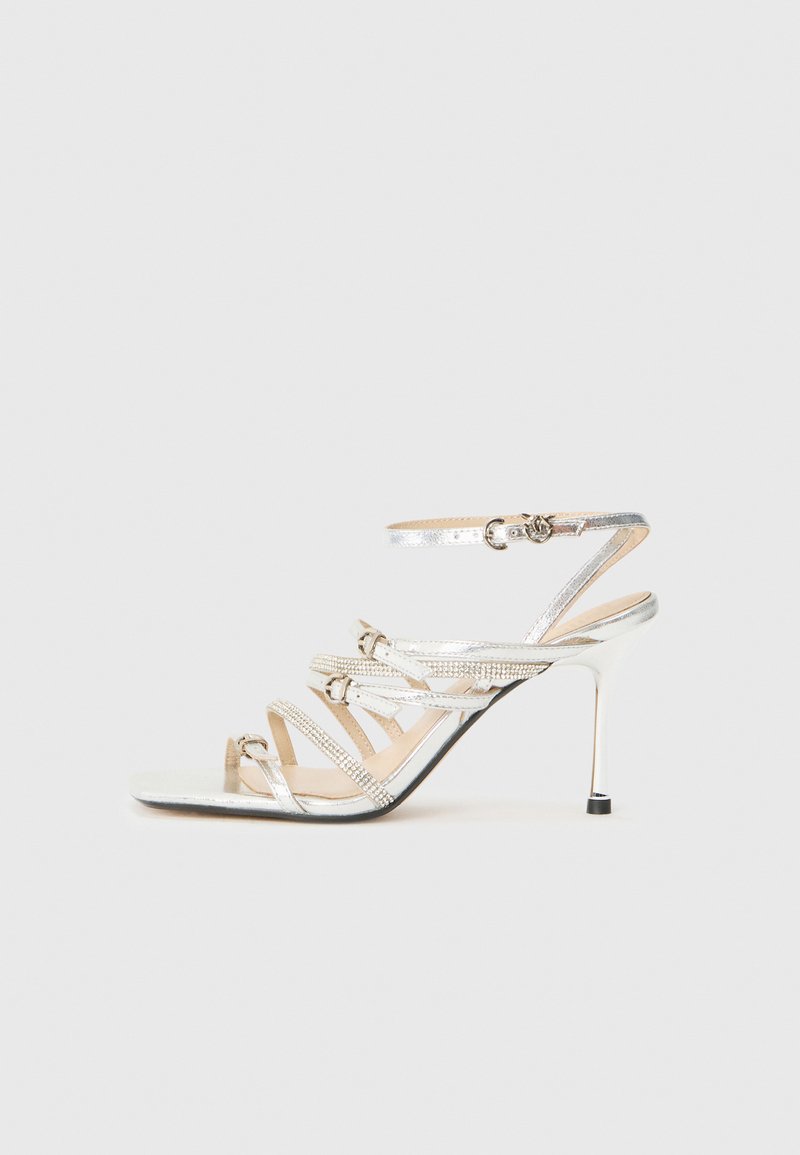 Silberne Sandalen mit Absatz, die mehrere überkreuzte Riemen, eine metallische Oberfläche und Strassakzente aufweisen. Offenes Zehendesign mit schlankem Stiletto-Absatz.