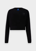 Schwarzer, kürzer geschnittener Pullover mit V-Ausschnitt, geripptem Saum und langen Ärmeln. Mit einem kleinen strukturierten Herzdetail auf der Brust. Hergestellt aus weichem Material.