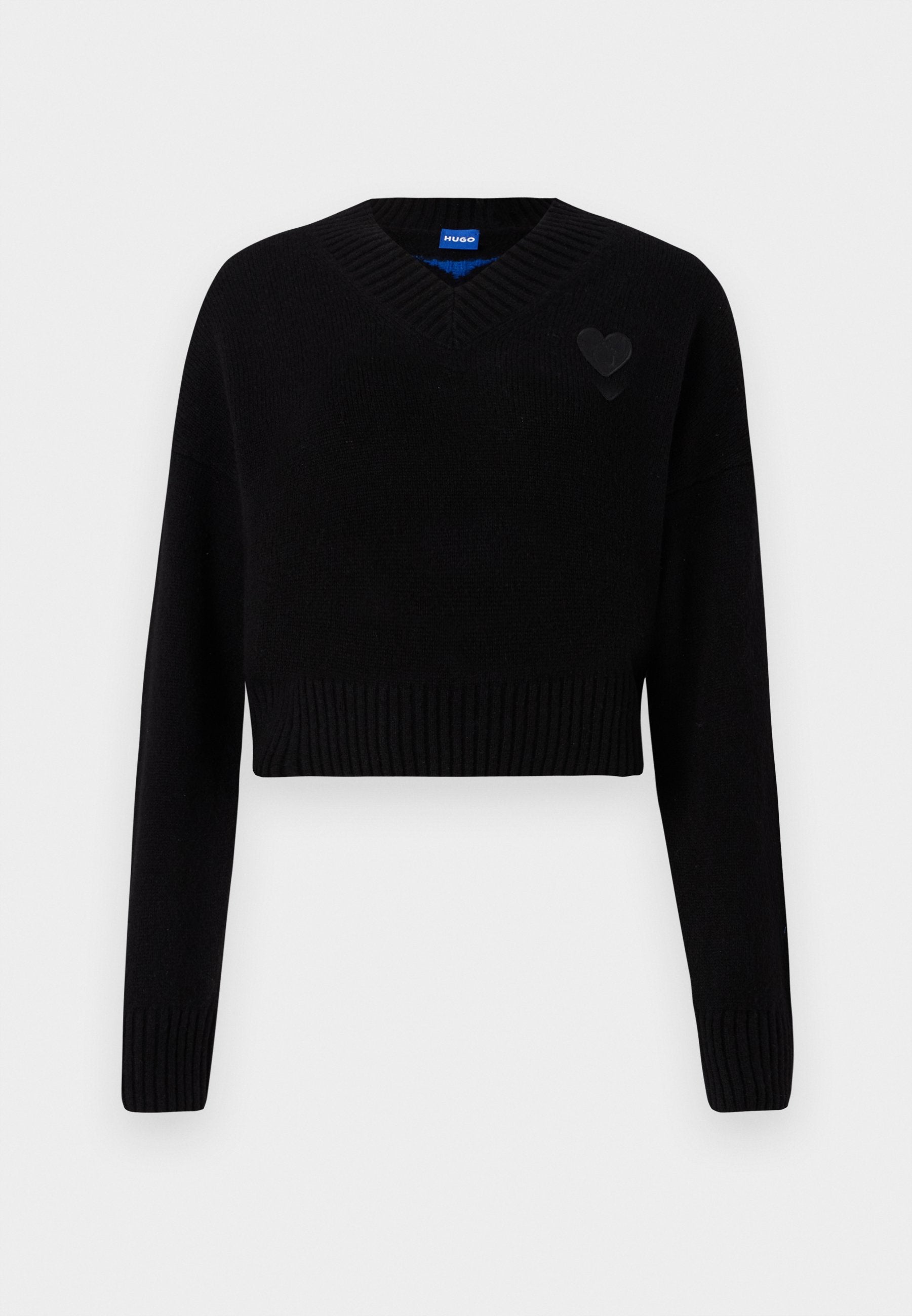 Schwarzer, kürzer geschnittener Pullover mit V-Ausschnitt, geripptem Saum und langen Ärmeln. Mit einem kleinen strukturierten Herzdetail auf der Brust. Hergestellt aus weichem Material.