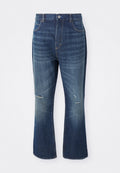 Blaue Jeans im Schlagstil mit leichter Abnutzung an beiden Knien und einem Knopfverschluss an der Taille, vor einem weißen Hintergrund präsentiert.