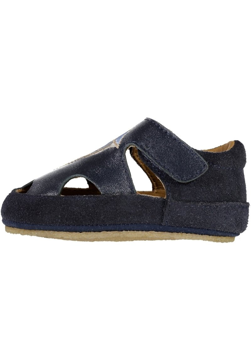 Kinder-Sandalen aus marineblauem Leder mit seitlichen Ausschnitten, Klettverschluss und beige gummierter Sohle, von der Seite gezeigt.