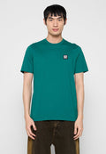 Petrolfarbenes Baumwoll-T-Shirt mit Rundhalsausschnitt, kurzen Ärmeln und einem kleinen schwarz-weißen Logo auf der linken Brustseite. Legere Passform.