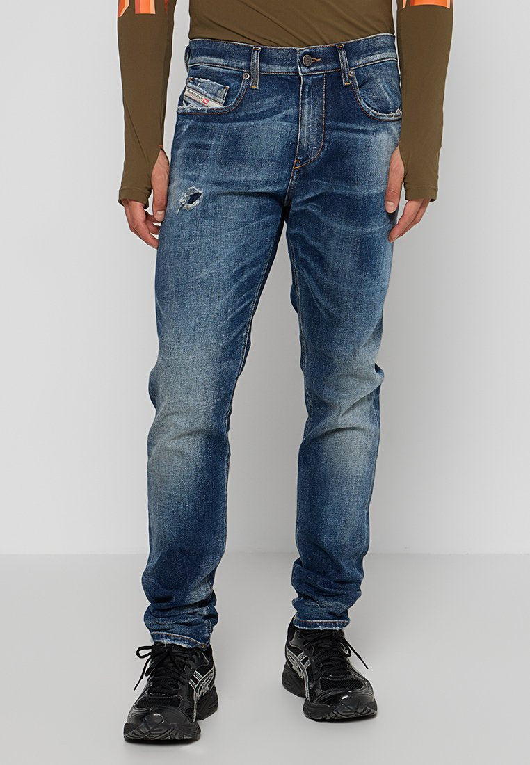 Blaue Denim-Jeans mit einem verblassten Waschlook, Slim-Fit, mit einem ausgefransten Bereich am linken Oberschenkel und klassischem Fünf-Taschen-Stil.