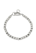 Silberne Metallarmband mit pyramidenförmigen Nieten, ausgestattet mit einem Gliederkettenschluss und einem stilisierten Verschluss. Glatte, reflektierende Oberfläche.